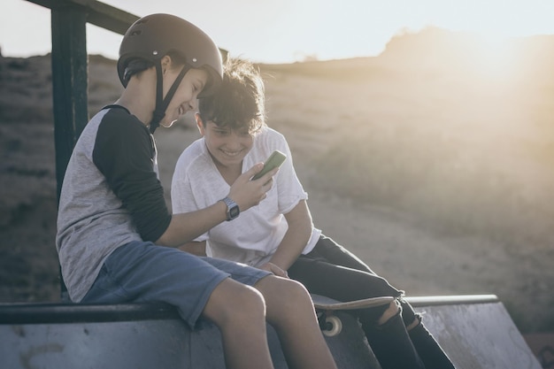 Friends looking at smart phone and smiling sitting outdoors