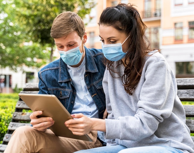 Photo friends looking at a tablet while wearing medical masks