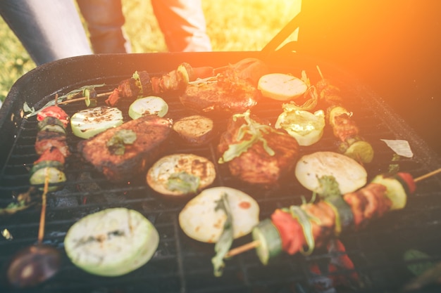 Friends making barbecue and having lunch in the nature. Couple having fun while eating and drinking at a pic-nic - Happy people at bbq party