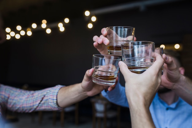 Foto amici facendo acclamazioni con bicchieri di whisky