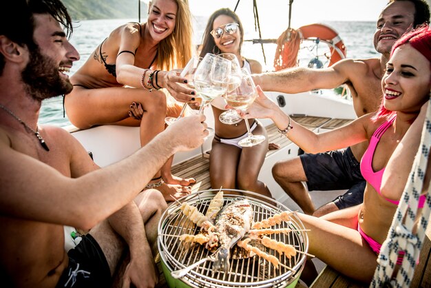 Amici che fanno il pesce barbecue sull'yacht