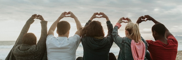 Amici che fanno l'amore con le mani del cuore in spiaggia