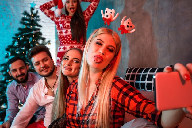 Friends making selfie while celebrating christmas or new year eve at home