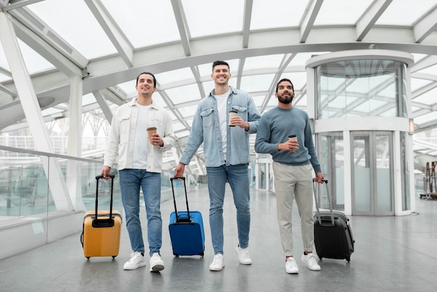 Friends Men Traveling Walking With Suitcases Holding Coffee In Airport