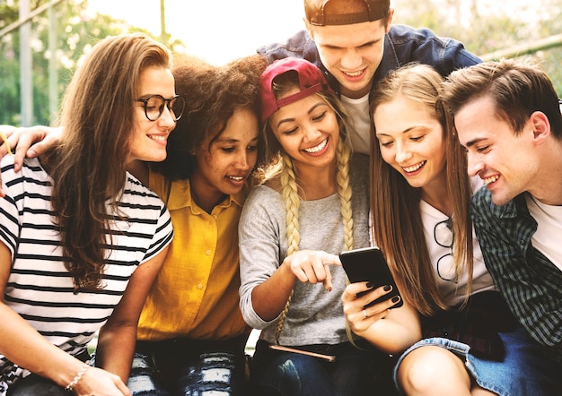 Friends in the park looking using smartphones millennial and youth culture concept