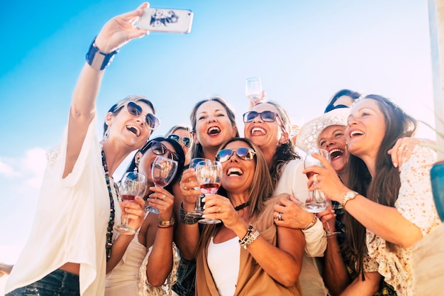 Foto gli amici del gruppo si divertono insieme nella festa dell'amicizia con vino rosso e foto selfie dal telefono