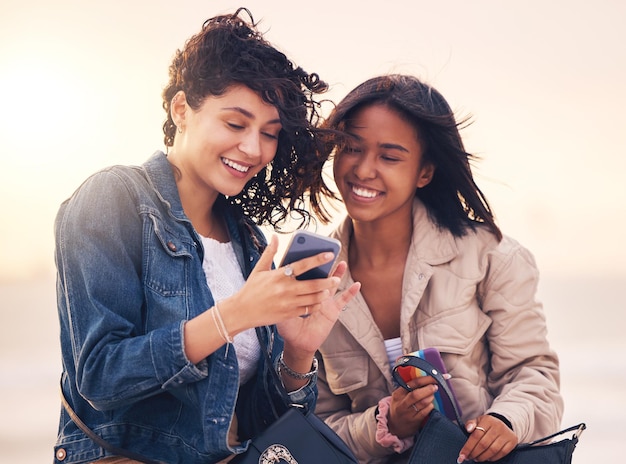 写真 友人の電話とソーシャル メディアの屋外で幸せな異人種間クリエイティブ コンテンツ ストリーミング ビデオ オンラインまたは web コミュニケーション メッセージ アプリ 女性の多様性と友情またはスマートフォンでの読書