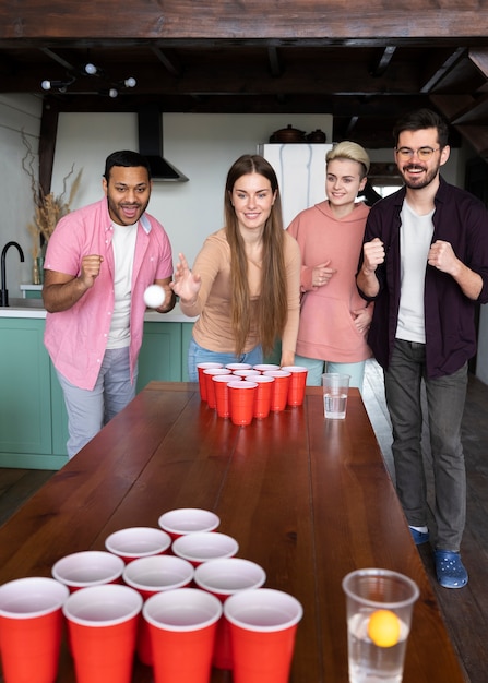 Photo friends playing beer pong together at a party