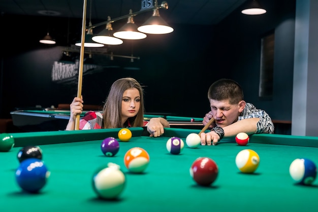 Friends playing billiard, man going hit a ball