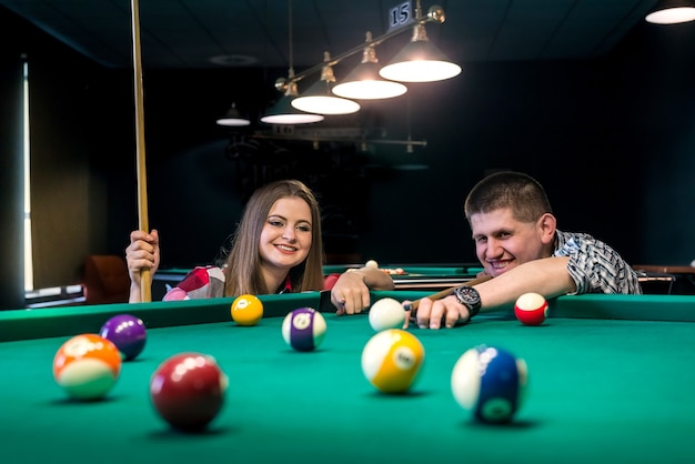 Friends playing billiard, man going hit a ball