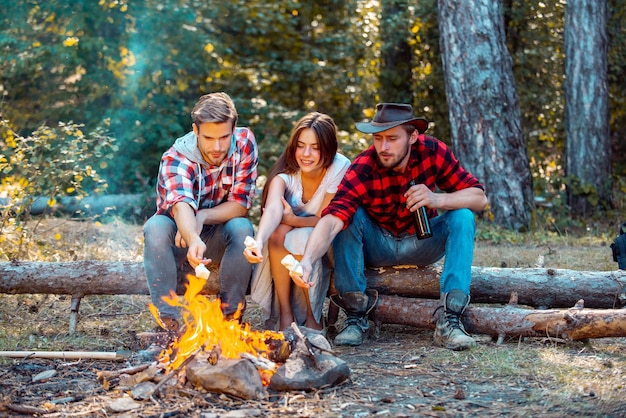 Friends relaxing near campfire after day hiking or gathering mushrooms friends enjoy weekend camp in