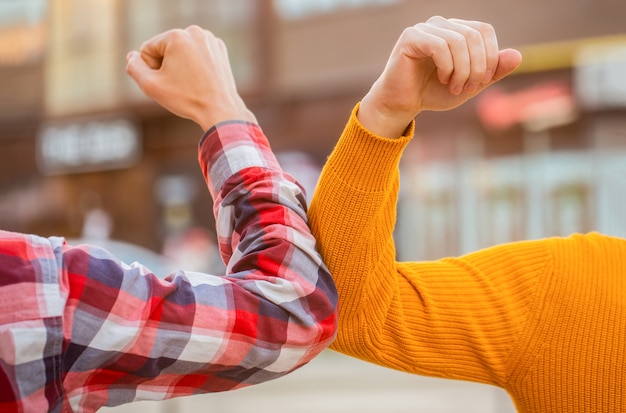 Friends shaking elbows outdoors.