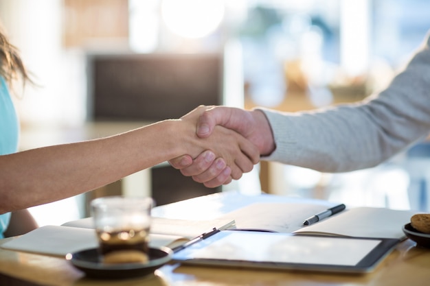 Friends shaking hands in cafe