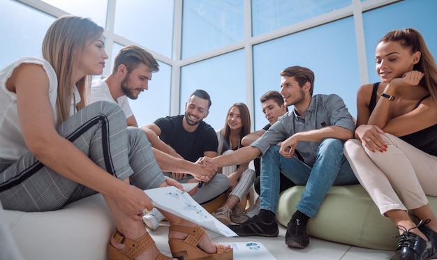 Friends shaking hands sitting on the floor in the new office