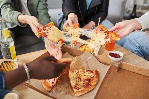 Photo friends sharing pizza with stretching cheese