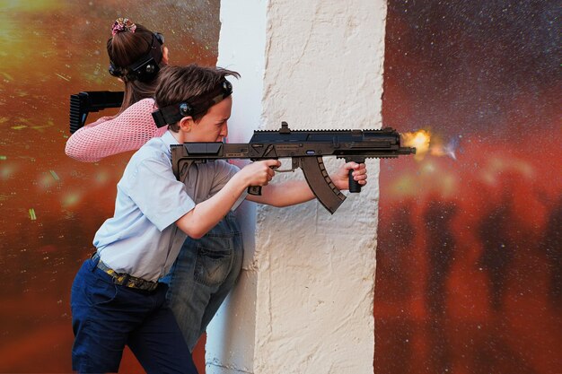 Photo friends shooting with toy rifles by wall