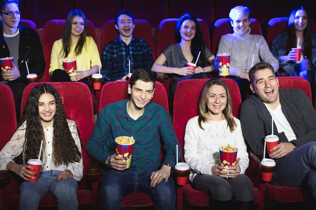 Friends sit in a cinema watch film eating popcorn and drinking aerated sweet water