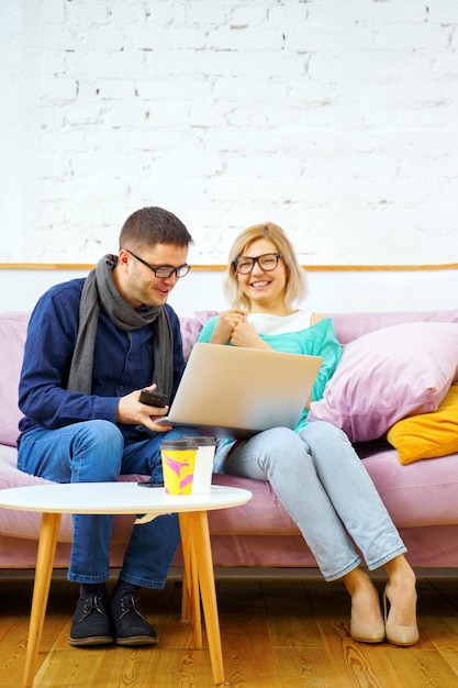 Gli amici si siedono sul divano a chiacchierare e utilizzano un computer desktop