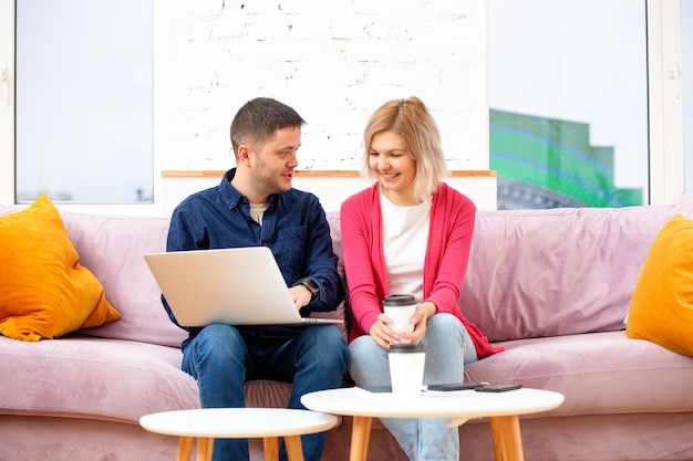 Friends sit on the couch chatting and using a desktop computer