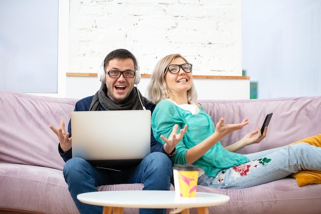 Friends sit on the couch chatting and using a smartphone desktop computer