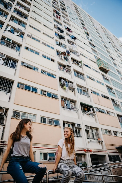 Photo friends sitting against buildings in city