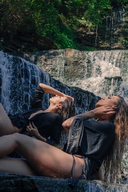 Foto amici seduti accanto a una cascata nella foresta