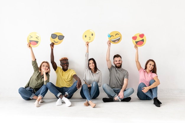 Friends sitting on floor and holding emoji