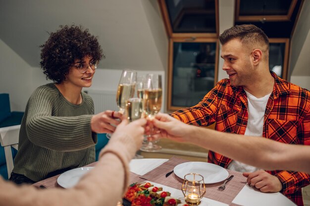 Friends sitting at a kitchen table and toasting during a dinner part