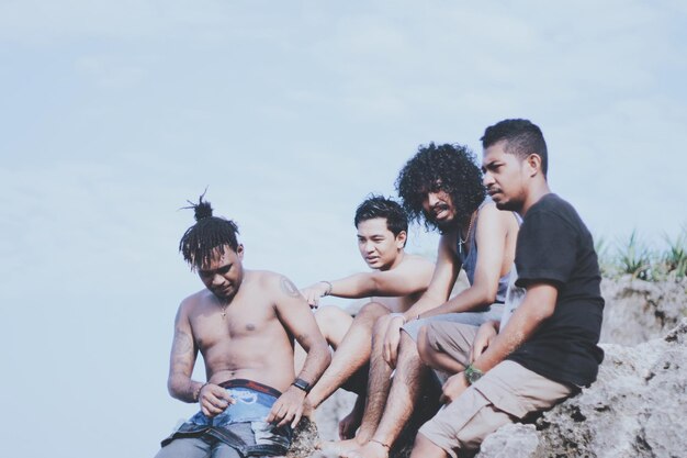 Photo friends sitting on rock against sky