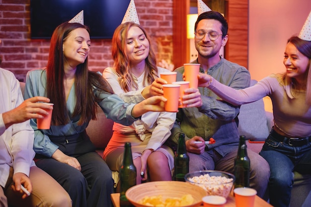 Friends sitting on a sofa in a cozy room and celebrating birthday