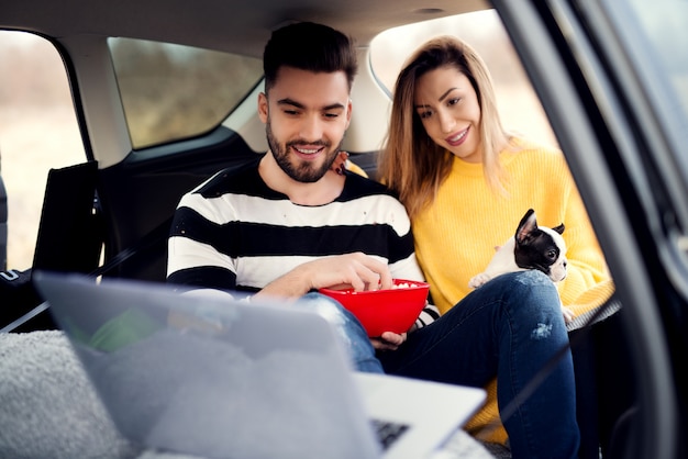 Premium Photo  Friends and a small puppy watching movie on their lap top.  having fun during a car trip.