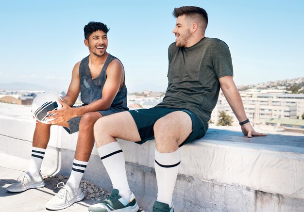 Photo friends sports and talking after soccer game on rooftop for urban sports exercise and training outdoor in summer athlete men have conversation about fitness football and city lifestyle with ball