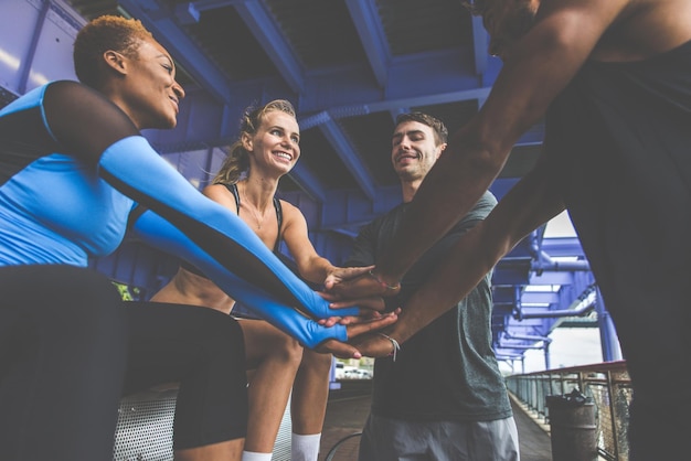 Photo friends stacking hands while standing under bridge