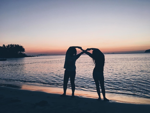 写真 夕暮れの海に立つ友人たち