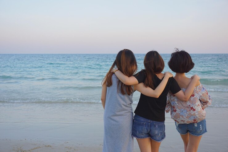 Photo 晴れた空の前でビーチに立っている友人たち