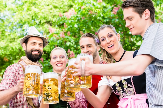 Friends standing under chestnut toasting with beer