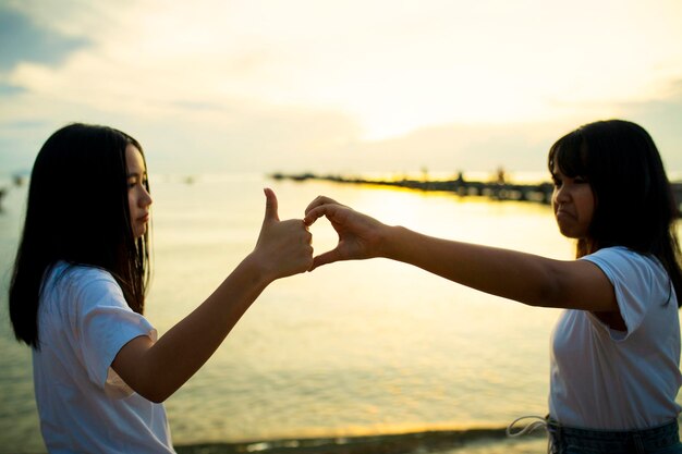 写真 夕暮れの空に向かってビーチに立っている友人たち