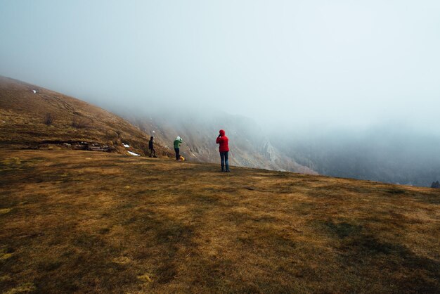 写真 霧の天候で山に立っている友人たち