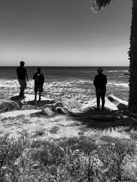 Foto amici in piedi su una roccia contro il mare sulla spiaggia