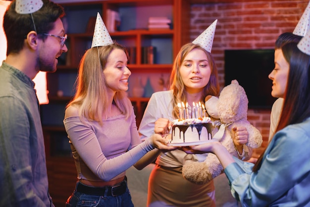 Friends standing together holding a plate with a cake and celebrating birthday