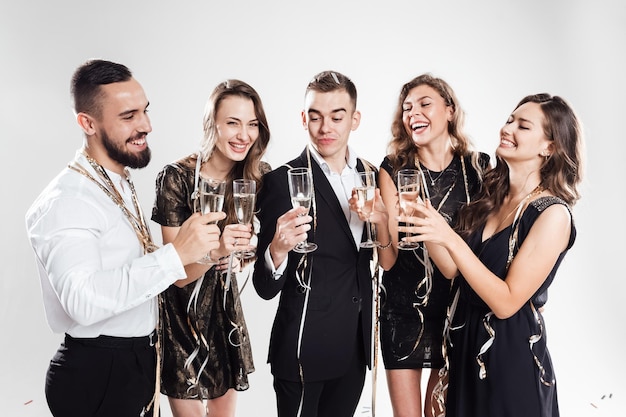 Friends in stylish elegant clothes smile together holding glasses of champagne in hands