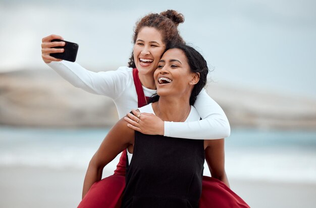 Photo friends, sun, sand and sea. shot of two friends taking a selfie at the beach.