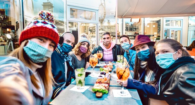 Friends taking selfie outside at cocktail bar - Selective focus on central part of frame