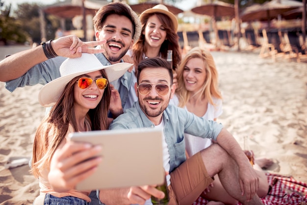 Friends taking selfie together on smart phone on beach