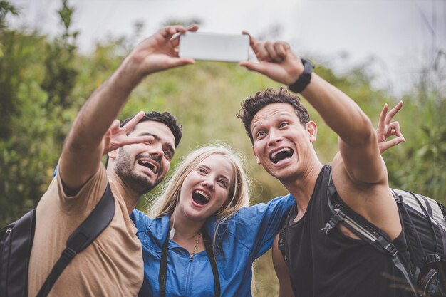 Foto amici che si fanno un selfie in piedi nella foresta