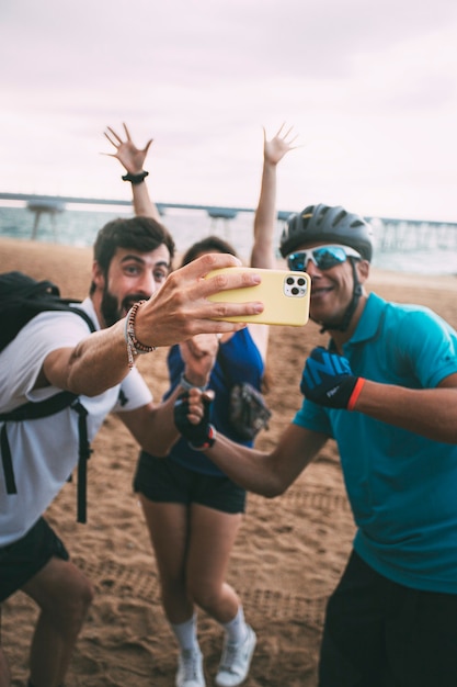 해변에서 휴대폰으로 셀카를 찍는 친구 손과 전화에 초점을 맞춘 우정 기술