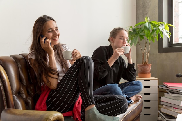 Foto amici che parlano al cellulare mentre bevono caffè a casa