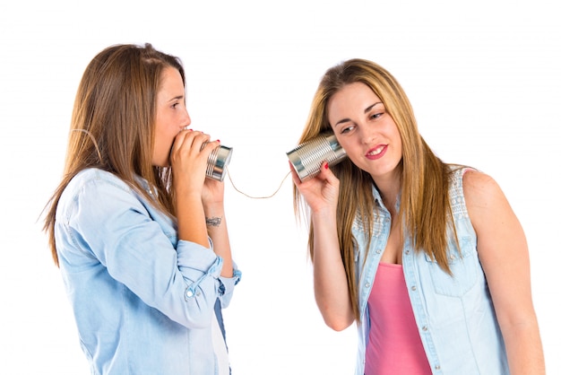 Friends talking through a tin phone over white background