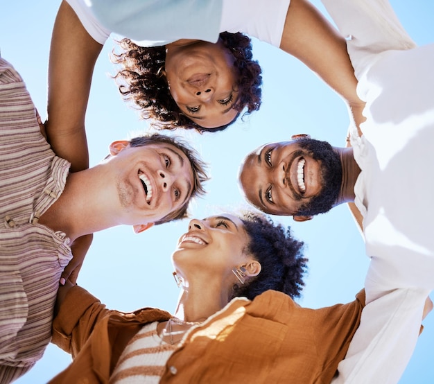 Foto lavoro di squadra degli amici e felice con un gruppo di uomini e donne solidali fuori in una calca o in cerchio su un cielo blu dal basso sorridi fiducia e collaborazione con persone felici insieme fuori