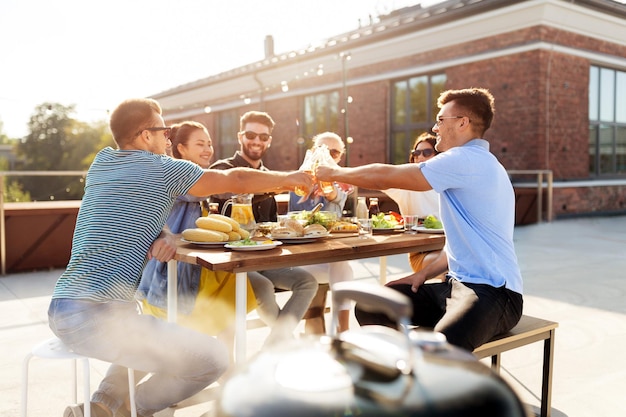friends toast drinks at barbecue party on rooftop